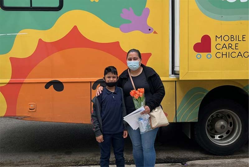 A mother and son pose in front of a Mobile Care Chicago truck.