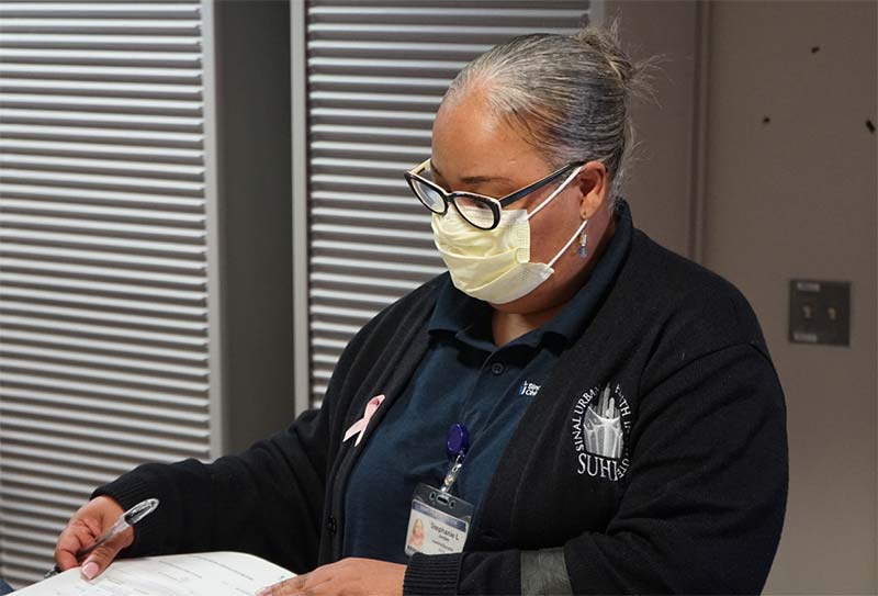 A health educator at Sinai Urban Health Institute filling out paperwork.